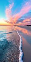 A beautiful sunset over the ocean with a pink and orange sky. The water is calm and the waves are small photo