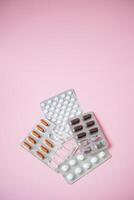 This colorful collection features various blister packs of pills, carefully arranged against a vivid pink background, creating a striking visual contrast that grabs attention photo