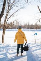 A woman dressed in a vibrant yellow jacket strolls through the stunning, pristine snow, all while carrying a bag and savoring a delightful winter day amidst natures icy, chilly weather photo