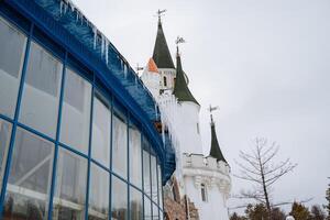 Imagine a magnificent building that prominently features a castle perched atop it, complete with beautiful icicles gracefully forming along the edges of the roof in the winter photo
