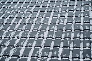 This closeup image showcases a rooftop blanketed in sparkling snow, highlighting the captivating textures and intricate patterns of delicate snowflakes. The scene is mesmerizing photo