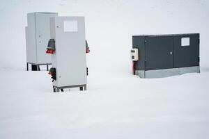 Three electrical boxes are currently positioned in the snow, with their surfaces covered in a layer of white frost, reflecting the cold, winter atmosphere all around them photo