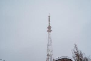 A very tall tower stands majestically against a backdrop of a cloudy sky, showcasing its significance in telecommunications and its role as a transmitter station for cellular networks photo