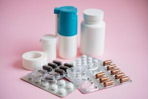 A vibrant and colorful assortment of various pills and bottles is artistically arranged against a soft pink background, resulting in a visually appealing display of healthrelated items photo