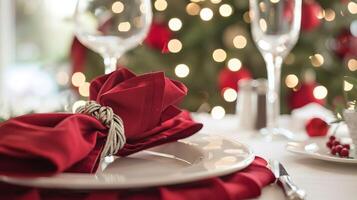 Elegant holiday table setting with red napkin and festive tree in background photo