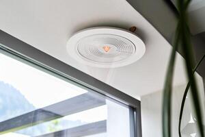 Modern ceiling smoke detector in bright minimalist room with large window photo
