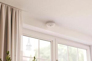 Modern home safety with ceiling smoke detector above large windows and curtains photo