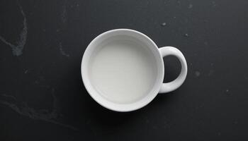 Overhead Shot of a White Mug Filled with Creamy Liquid on a Dark Marble Surface photo