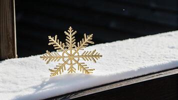 A golden snowflake sits on top of a snowy window sill photo
