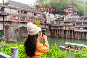 Young female tourist taking a photo of the Feng Huang Ancient Town