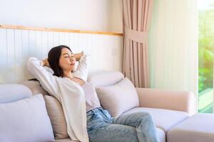 Asian woman relaxing and sitting on a sofa at home in the morning photo