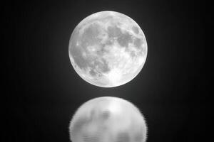 A striking black and white image of a full moon reflected in calm water, creating a serene and mystical atmosphere photo
