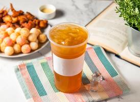 Iced green tea with ice cube served in plastic glass with ice cube isolated on napkin side view of taiwan cold drink photo