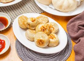 Shanghai Fried Buns 8 piece with Dipping Sauce served in plate isolated napkin side view of chinese dim sum food photo