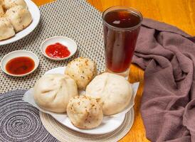 2 Steamed Buns, 2 Friend Buns with Dipping Sauces and a tall glass of iced tea isolated on napkin side view of taiwan dim sum food photo