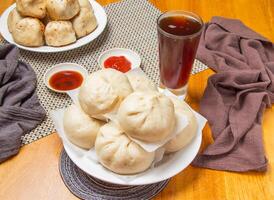 6 steamed pepper meat buns with Dipping Sauces and a tall glass of iced tea isolated on napkin side view of taiwan dim sum food photo