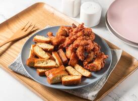 Fried chicken legs and dried tofu served in plate with fork isolated on napkin side view of taiwan food photo
