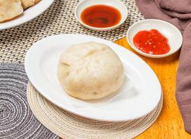 Steamed Pepper Pork Buns with Dipping Sauce served in plate isolated napkin side view of chinese dim sum food photo