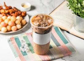 Iced cream milk tea with boba and ice cube served in plastic glass with ice cube isolated on napkin side view of taiwan cold drink photo