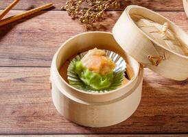 Shrimp Siew Mai Steamed Shrimp Dumpling in Bamboo Steamer with chopsticks isolated on wooden table side view of dim sum taiwan food photo