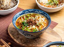Taiwanese Noodle Soup topping with mince meat served in bowl with chopsticks and spoon isolated on wooden board side view of taiwan food photo