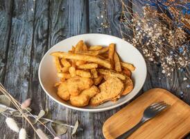 Crispy Chicken Nuggets and French Fries served in plate with fork isolated on wooden table side view of taiwan fried food photo