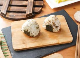 Grilled Rice Ball or Onigiri with Nori and Sesame Seeds served on wooden board with chopsticks side view of taiwan food photo