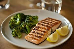 Close-up of a delicious grilled salmon steak with a side of fresh broccoli and lemon slices on a wooden surface. A perfect combination of flavors and textures for a healthy dinner photo