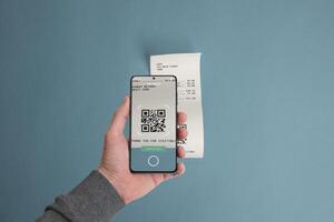 Smartphone scanning a QR code on a paper receipt placed on a table, illustrating the concept of paying bills digitally using mobile technology photo
