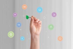 Hand holding a dart surrounded by various online shopping icons, symbolizing precision and strategy in targeting e-commerce goals and digital consumer engagement photo