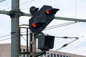 A railroad signal shows red lights indicating caution along a track in photo