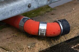 Red drainage pipe connecting to concrete surface in industrial area photo