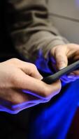 Young man playing mobile game with fast finger movements and colorful pulsating hand lights, dynamic gameplay, close up phone screen, digital entertainment, gaming action, energetic gaming session. photo