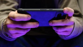 Young man playing mobile game with fast finger movements and colorful pulsating hand lights, dynamic gameplay, close up phone screen, digital entertainment, gaming action, energetic gaming session. photo