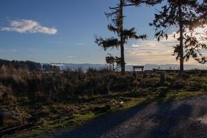 An empty park bench beside a trail facing distant mountains photo