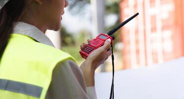 Close-up of a construction supervisor using a walkie-talkie for communication at a project site photo
