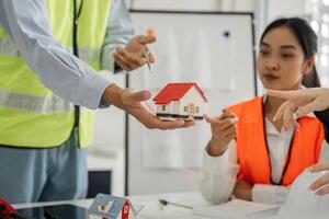 Construction team discussing project plans with a miniature house model in a modern office setting photo