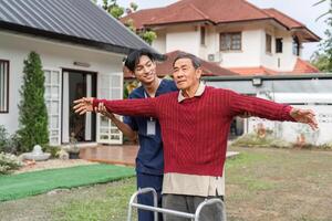 Nurse encouraging elderly man to stretch arms while using walker in a supportive garden environment photo