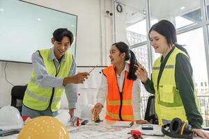 Joyful construction team engaging in brainstorming session with project plans and safety gear in a modern office photo