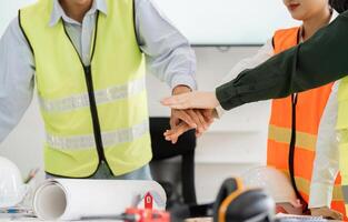 Construction team emphasizing teamwork with hands together in a project planning session photo