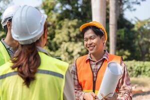 Logistics engineering team celebrating project milestones and discussing blueprints on a sunny construction site photo