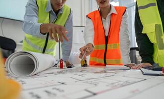 Construction team pointing at project plans and discussing layout details in a professional office setting photo
