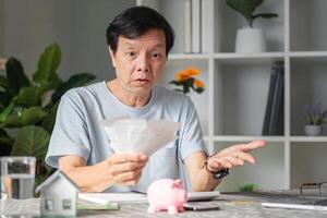 Surprised man shocked by financial problems and expenses while reviewing bills at home office photo