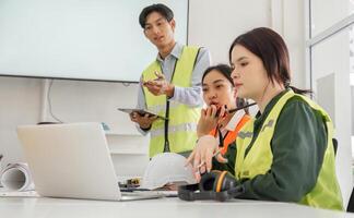 Construction team in a modern office discussing project updates with safety gear and technology in use photo