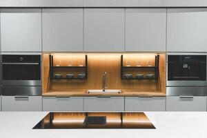 a sleek and modern kitchen sink and faucet set against a backdrop of dark cabinetry and a marble countertop. The faucet is a single-handle design with a tall photo