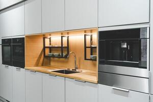 a sleek and modern kitchen sink and faucet set against a backdrop of dark cabinetry and a marble countertop. The faucet is a single-handle design with a tall, arched spout and a black matte finish photo