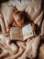 baby is reading a cartoon animal book while laying on a bed. photo