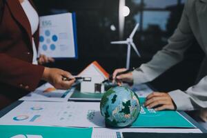 Business people working on a project with a globe and wind turbines photo