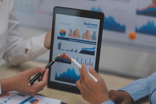 Two people are looking at a tablet with graphs on it photo