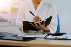 A woman is writing in a notebook while sitting at a desk photo